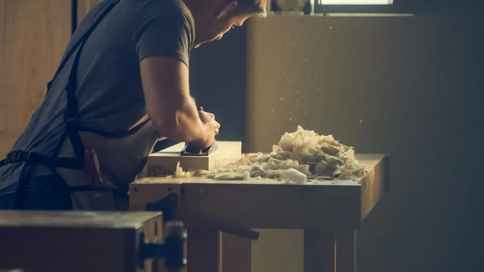 A joiner shaping timber at a workbench