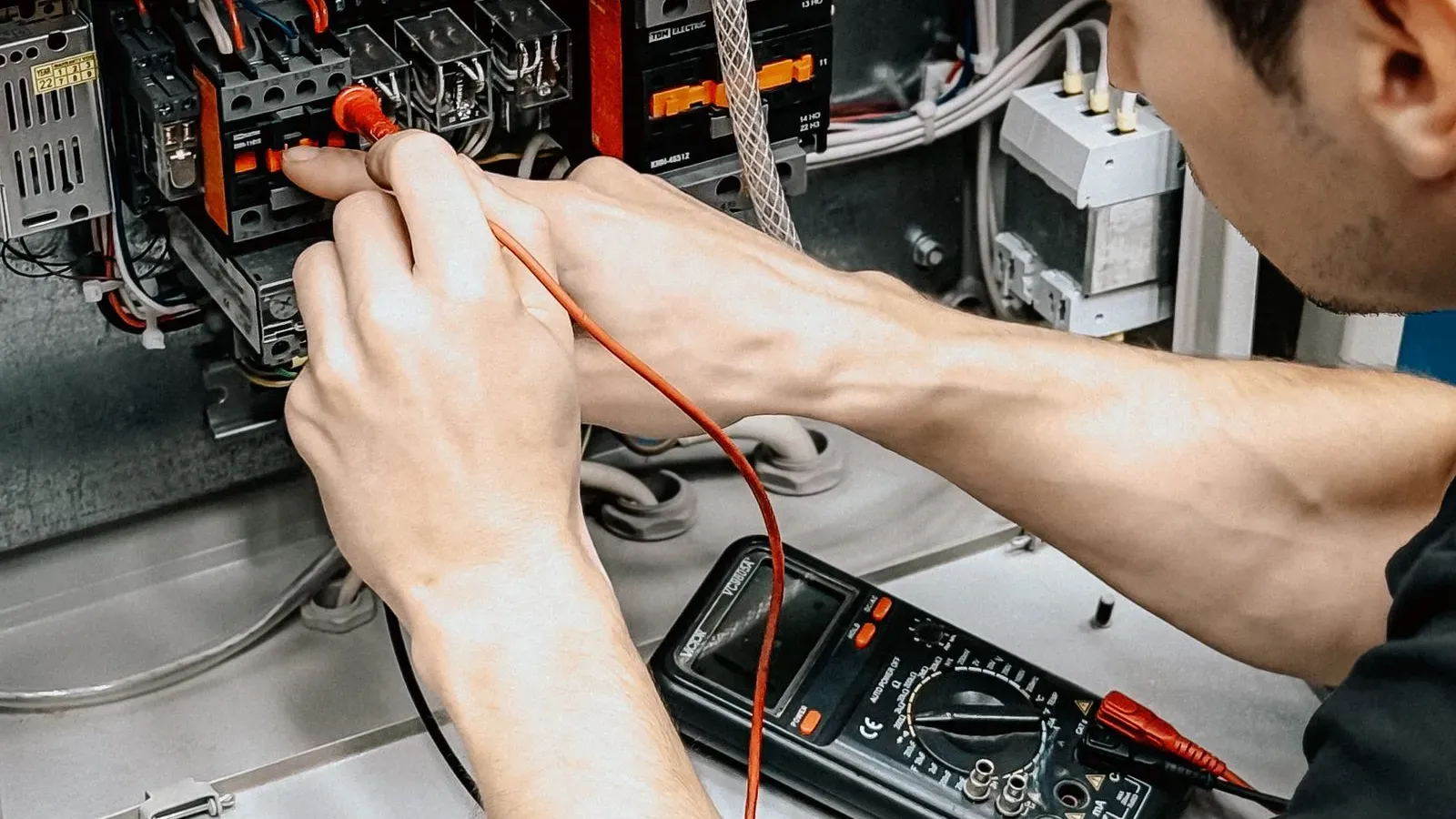 An electrician testing a consumer unit with a multimeter
